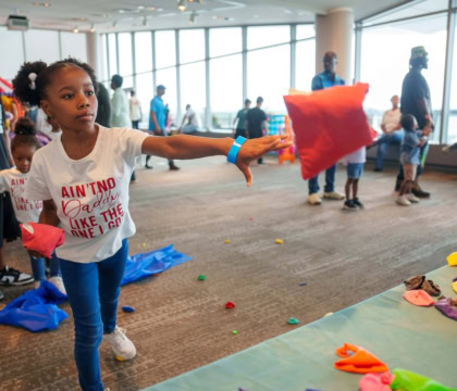 Girl throwing bean bag into air towards carnival game