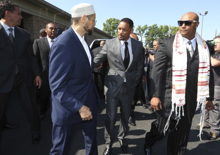 Will Smith stands with two men in suits