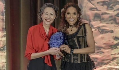 Two women posing for camera while holding an award