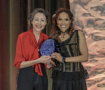 Two women posing for camera while holding an award