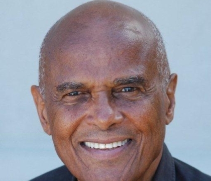 Harry Belafonte, wearing black button-up shirt, smiles at camera