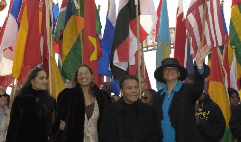 Photo of Muhammad Ali, Lonnie and two daughters with flags behind them