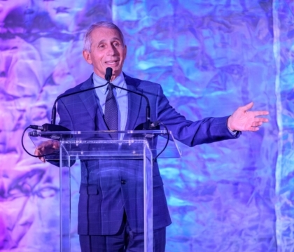 Dr. Fauci in a suit speaking at a lectern
