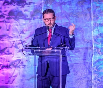 Man with glasses in a suit speaking at a lectern