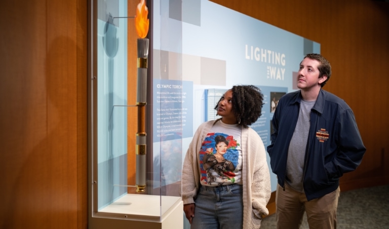 Two people looking at an Olympic torch in an exhibit