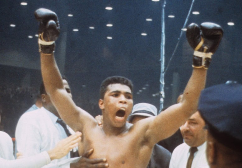 Photo of Muhammad Ali celebrating with gloves in the air