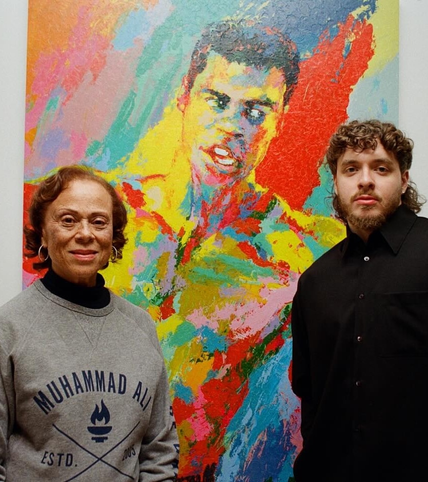 Photo of Lonnie Ali and Jack Harlow standing in front of Muhammad Ali painting and smiling at camera