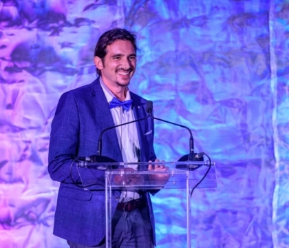 Man in a suit smiling in front of a lectern