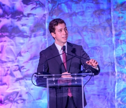 Man in a suit speaking at a lectern