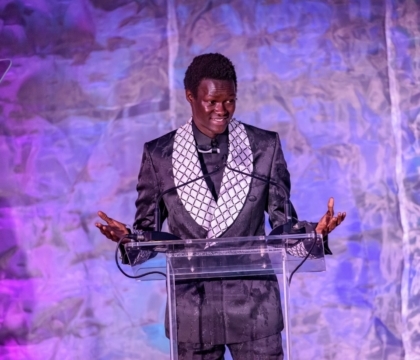 Man in an ornate jacket speaking at a lectern