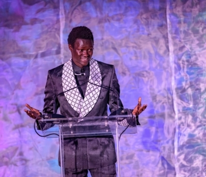 Man in an ornate jacket speaking at a lectern