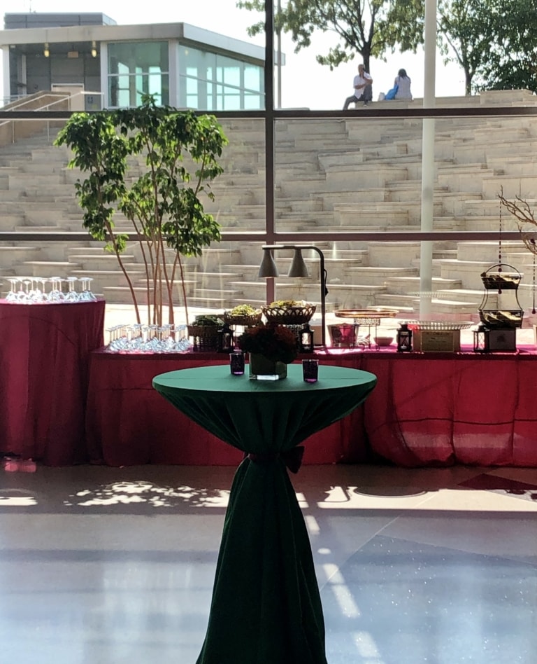 Room with a large glass wall and terrazzo flooring set up for an event with a buffet and tables