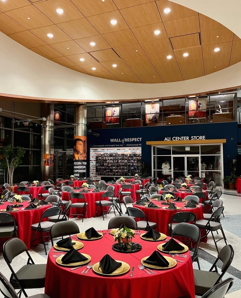 Room with a large glass wall and terrazzo flooring set up for an evening event with banquet round tables and chairs