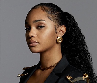 Woman in black jacket with gold accessories turning toward camera