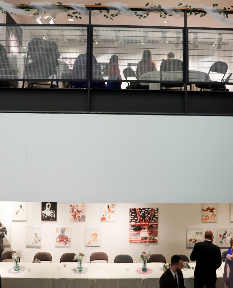 A split-floor event space with tables and people in semi-formalwear