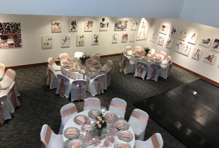 Art gallery set up for an event with large banquet rounds and chairs