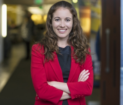 Woman wearing red jacket and black dress smiles for camera