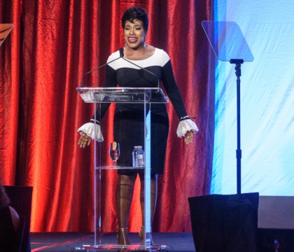 Woman with black and white dress speaks at lecturn