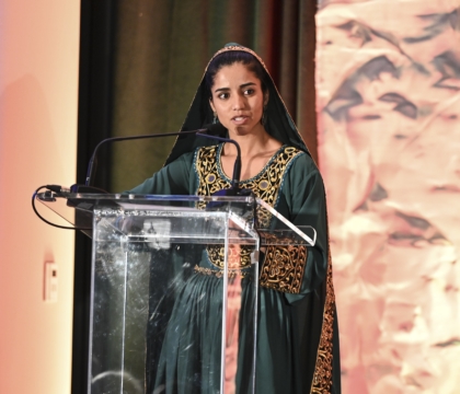 Woman wearing green outfit speaking at lecturn