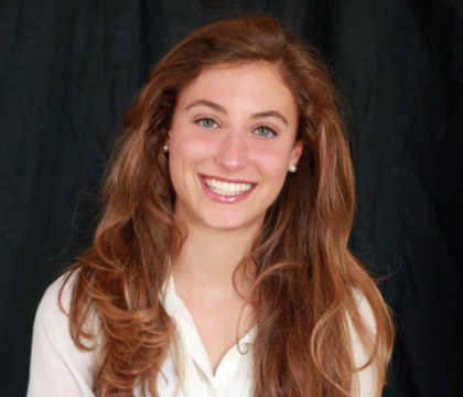 Woman with white blouse crosses arms and smiles at camera