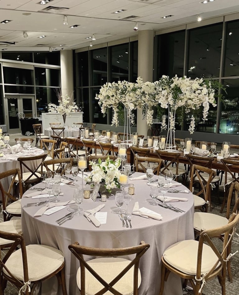 Event space with a long table, banquet rounds, and chairs decorated for a wedding reception