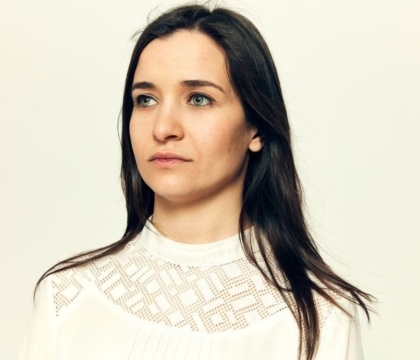 Woman with dark hair and white shirt looking off-camera