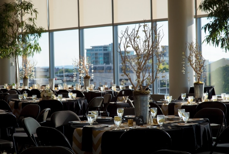Room with large windows set up for a an event with round tables