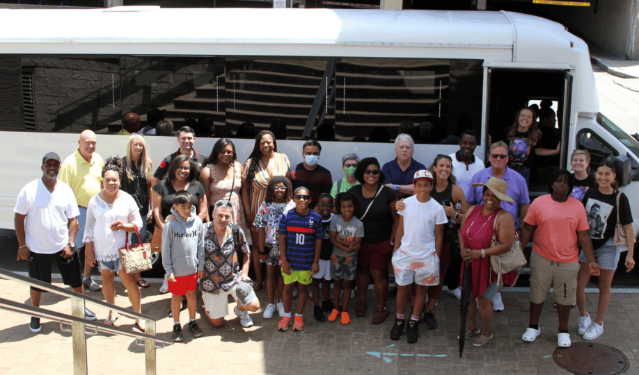 Group of people standing outside a bus smiling at camera