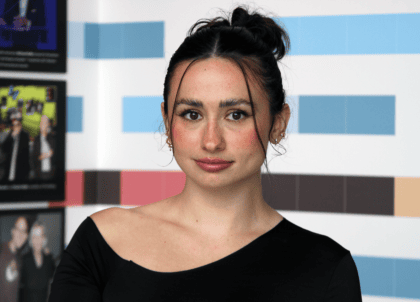 Photo of woman with dark hair tied up smiling at camera